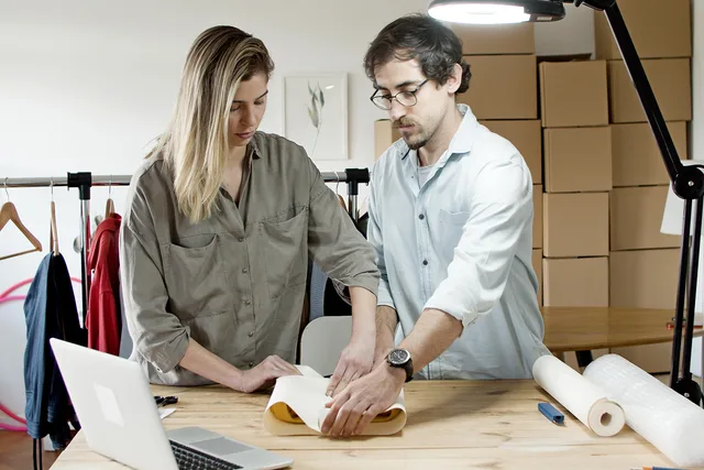 Team members packing orders in an online store's workspace, exemplifying efficient teamwork. Verpackungsprozess im Onlineshop standardisieren: Arbeitsschritte und Material